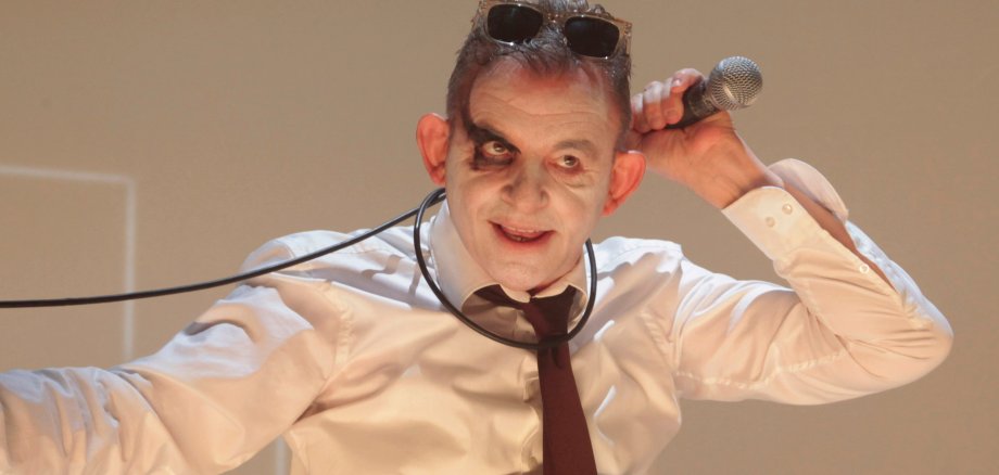 Männlicher geschminkter Schauspieler schlingt Mikrofon um den Hals