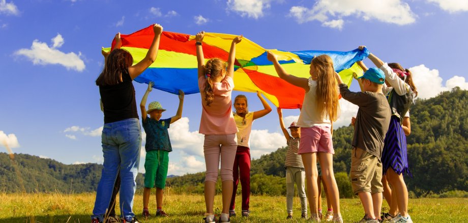 Mehrere Kinder halten ein Tuch über den Köpfen