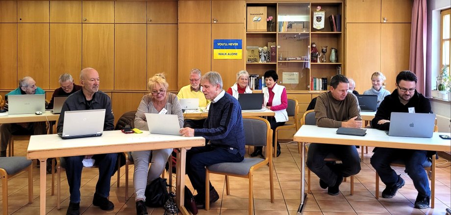 Teilnehmer des Internetcafé's an Tischen sitzend mit PC-Geräten
