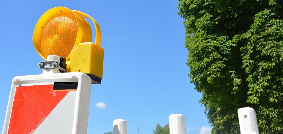 Teil einer rot-weißen Absperrbarke mit gelbem Licht