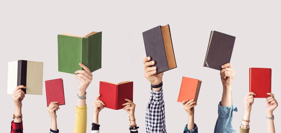 Mehrere Hände nebeneinander halten Bücher in die Höhe